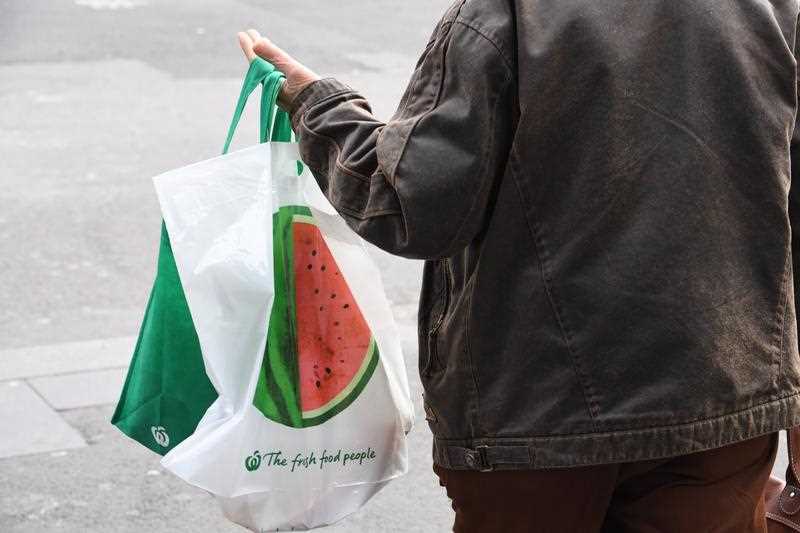 A person holds a Woolworths reusable shopping bag.