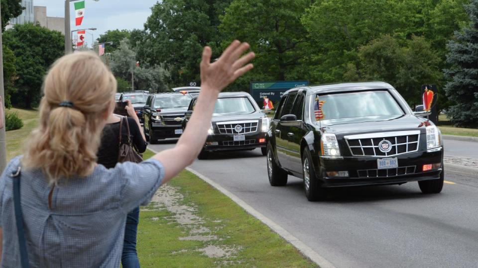 A woman waves as U.S. President Barack Obama’s motorcade passes by as he arrives for the North American Leaders’ Summit in Ottawa on June 29. THE CANADIAN PRESS/Paul Chiasson