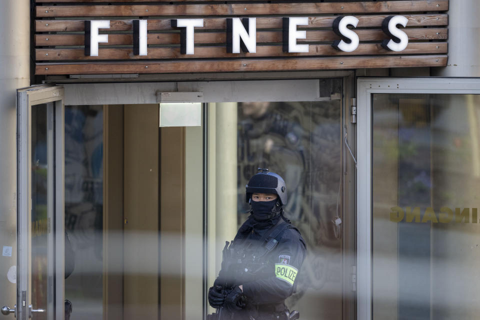 An armed police officer stays in front of a health club in Duisburg, Germany, Tuesday, April 18, 2023. German police say several people have been injured in an attack at a gym in the western city of Duisburg. Tuesday evening’s attack occurred in the old city of Duisburg and police asked residents to avoid the area. (Christoph Reichwein/dpa via AP)