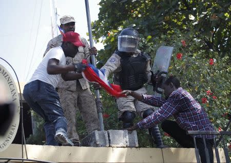 Haitian police officers try to stop protesters from raising the Haitian flag at the consulate of the Dominican Republic in Port-au-Prince February 25, 2015. REUTERS/Andres Martinez Casares