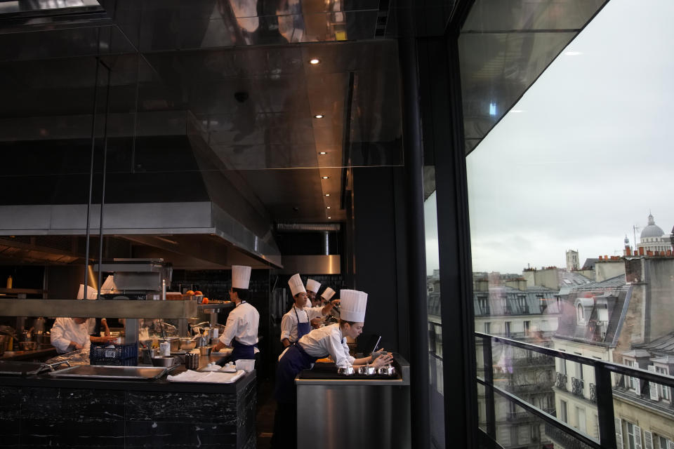 Cooks prepare food at La Tour d'Argent restaurant in Paris, Wednesday, Dec. 13, 2023. The Tour d'Argent, which claims to be the oldest restaurant in the French capital, has a front-row view of the renaissance of Notre Dame Cathedral as artisans prepare the fire-ravaged monument for reopening next year. The high-end restaurant, which helped inspire the movie "Ratatouille,'' recently reopened after its own renovation that preserved traditions while adapting to the 21st century. It will also overlook the opening ceremony of the Paris Olympics on July 26, 2024. (AP Photo/Christophe Ena)