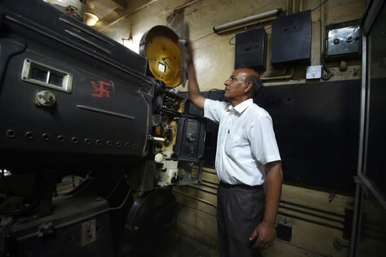 Indian projectionist Ramesh Kumar, who has worked at the Regal cinema for 23 years, looks at an old projector at the 84-year-old movie hall