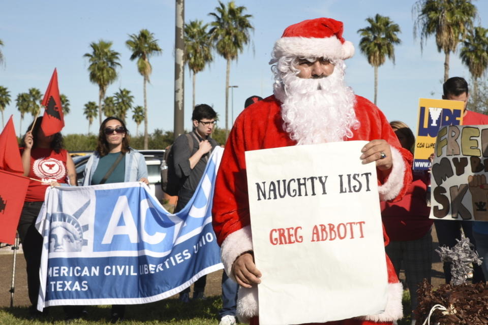 Organizaciones activistas protestan --incluido un hombre vestido de Santa Claus que sostiene un letrero que dice que el gobernador de Texas, Greg Abbott, está en la lista de los que se portaron mal-- antes de una conferencia de prensa en la que Abbott promulgó tres iniciativas de seguridad fronteriza en el estado, el lunes 18 de diciembre de 2023, en Brownsville, Texas. (AP Foto/Valerie Gonzalez)