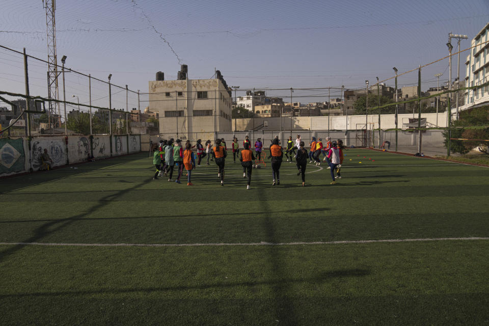 Palestinian girls warm-up during a soccer training session at the Beit Hanoun Al-Ahli Youth Club's ground in the northern Gaza strip, Tuesday, Oct. 29, 2022. Women's soccer has been long been neglected in the Middle East, a region that is mad for the men's game and hosts the World Cup for the first time this month in Qatar. (AP Photo/Fatima Shbair)