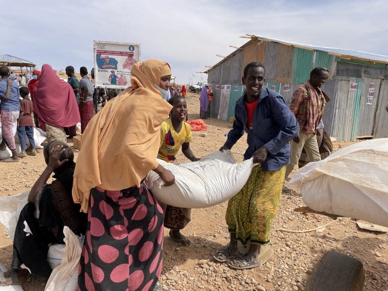 A family in Ethiopia loads a bag of emergency relief grain onto a cart.