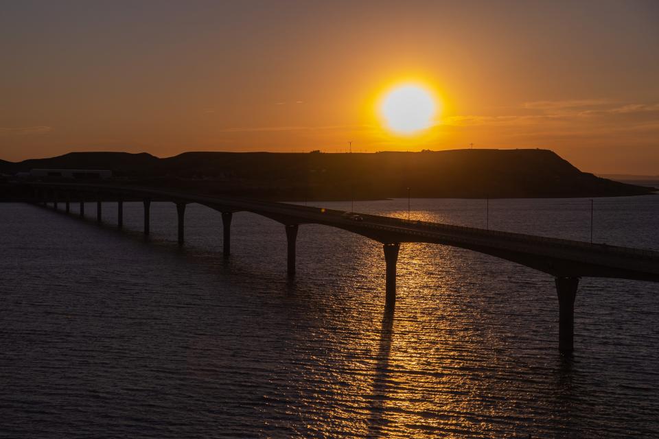 The sun sets over the Missouri River and the Four Bears Memorial Bridge in New Town, N.D.