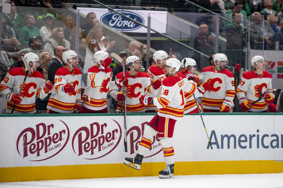 Calgary Flames left wing A.J. Greer (18) fist-bumps teammates after scoring a goal during the first period of an NHL hockey game against the Dallas Stars, Friday, Nov. 24, 2023, in Dallas. (AP Photo/Emil T. Lippe)