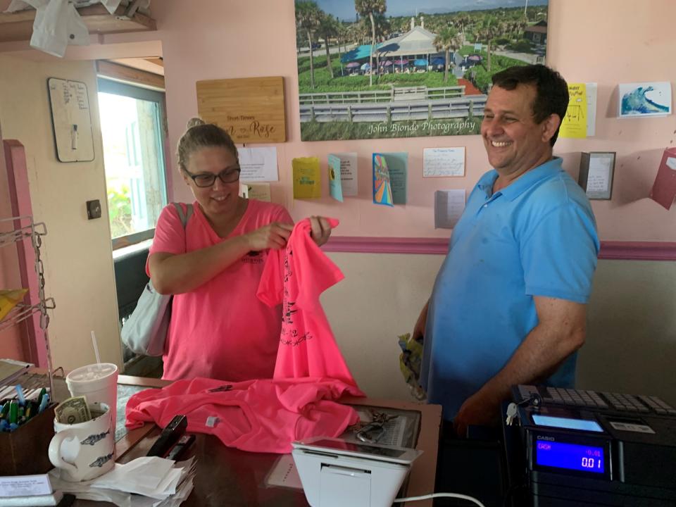 Amy Jacobs shows off a T-shirt commemorating the Culumber family's 30 years of operating the Jaycee Park Seaside Grill in Vero Beach Wednesday April 6, 2022. The Culumber family, including owner Dan Culumber, right, will retire April 23, 2022.