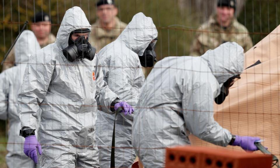 Soldiers wearing protective coveralls work to remove a vehicle connected to the nerve agent attack in the UK.