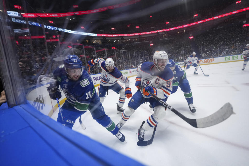 Vancouver Canucks' Nils Hoglander (21) and Edmonton Oilers' Connor McDavid (97) vie for the puck during the first period of Game 1 of a second-round NHL hockey Stanley Cup playoffs series, Wednesday, May 8, 2024, in Vancouver, British Columbia. (Darryl Dyck/The Canadian Press via AP)