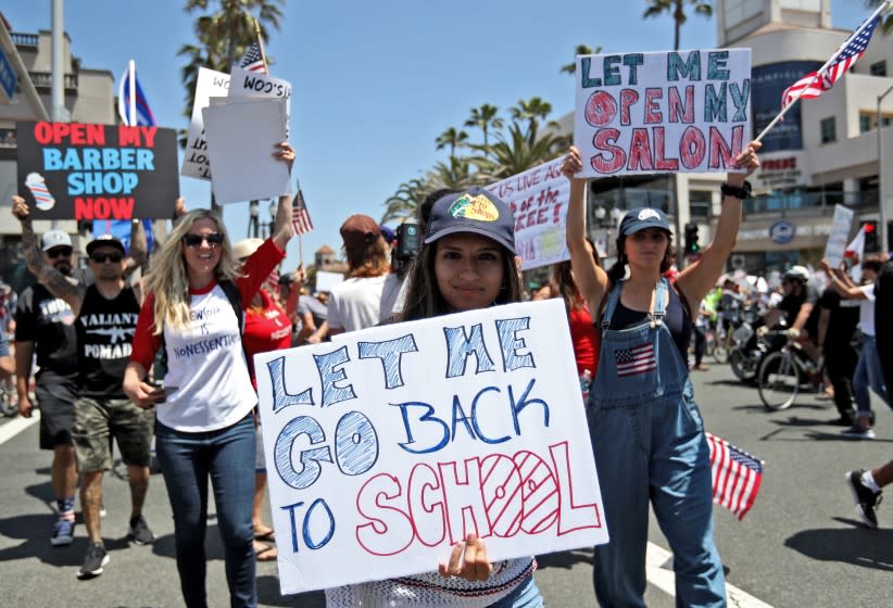 Protesters hold signs up during the "Live Free Protest to Open CA." protest at Main and Pacific Coast Highway in Huntington Beach on Friday, May 1, 2020. Governor Gavin Newsom closed all Orange County beaches the day before.