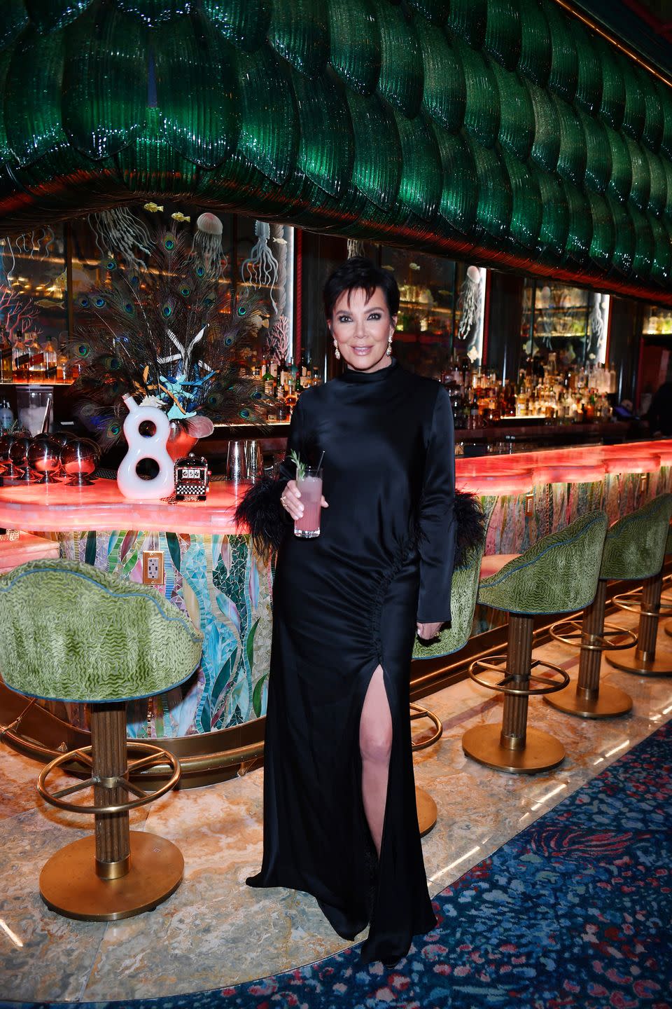 kris jenner wearing a black dress, posing in front with a pink drink in her hand, in front of the 818 tequila display at the mayfair supper club at bellagio resort casino on june 23, 2023 in las vegas, nevada