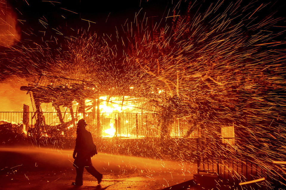 A firefighter passes a burning home as the Hillside fire burns in San Bernardino, Calif., on Thursday, Oct. 31, 2019. The blaze, which ignited during red flag fire danger warnings, destroyed multiple residences. (AP Photo/Noah Berger)