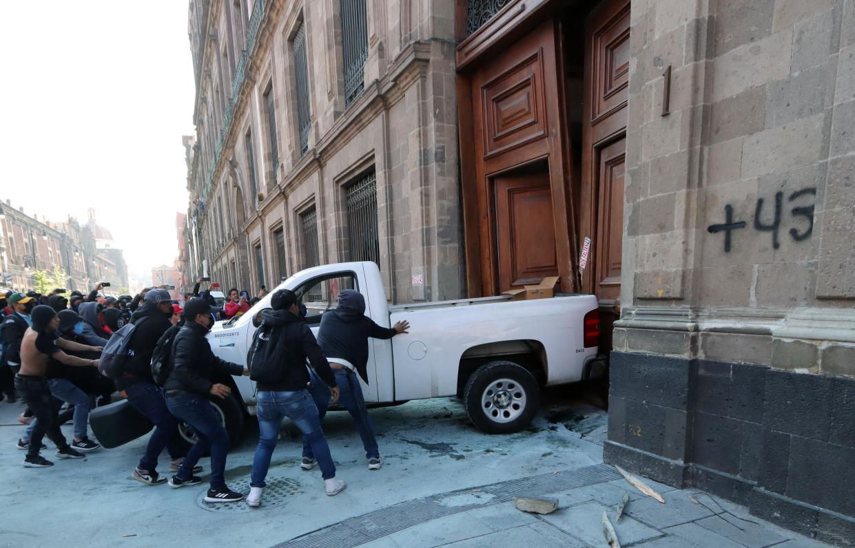 Manifestantes que protestaban por la desaparición de 43 estudiantes en Ayotzinapa tiraron la puerta de Palacio Nacional ante la negativa del presidente Andrés Manuel López Obrador de entrevistarse con ellos. | Foto: VALENTINA ALPIDE / AF via Getty Images