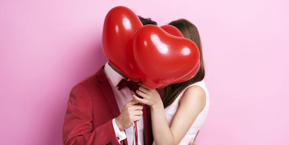 couple kissing behind balloons