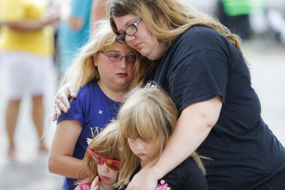 Mourners embrace after bringing flowers to a makeshift memorial Tuesday, Aug. 6, 2019, for the slain and injured in the Oregon District after a mass shooting that occurred early Sunday morning, in Dayton, Ohio. (AP Photo/John Minchillo)