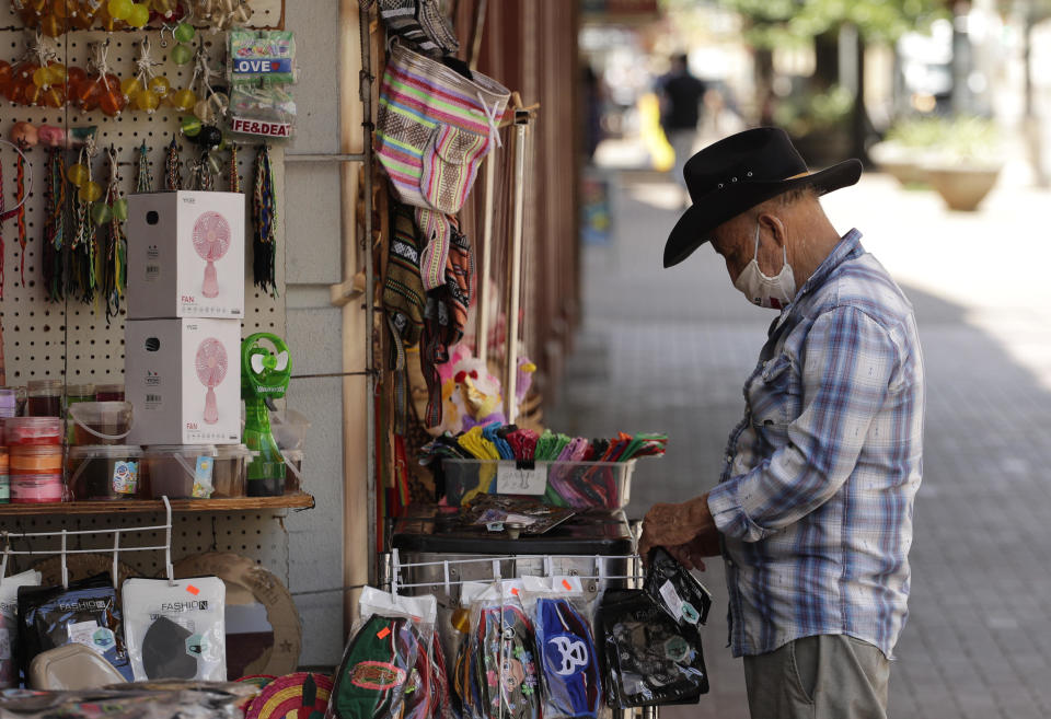 A vendor wearing a mask to protect against COVID-19 arranges merchandise at his business in San Antonio on Monday, July 20, 2020. Cases of COVID-19 continue to spike in Texas. / Credit: Eric Gay / AP