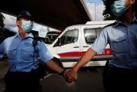 Police officers escort a prison van which is carrying Tong Ying-kit, the first person charged under the new national security law, as he leaves West Kowloon Magistrates' Courts, in Hong Kong