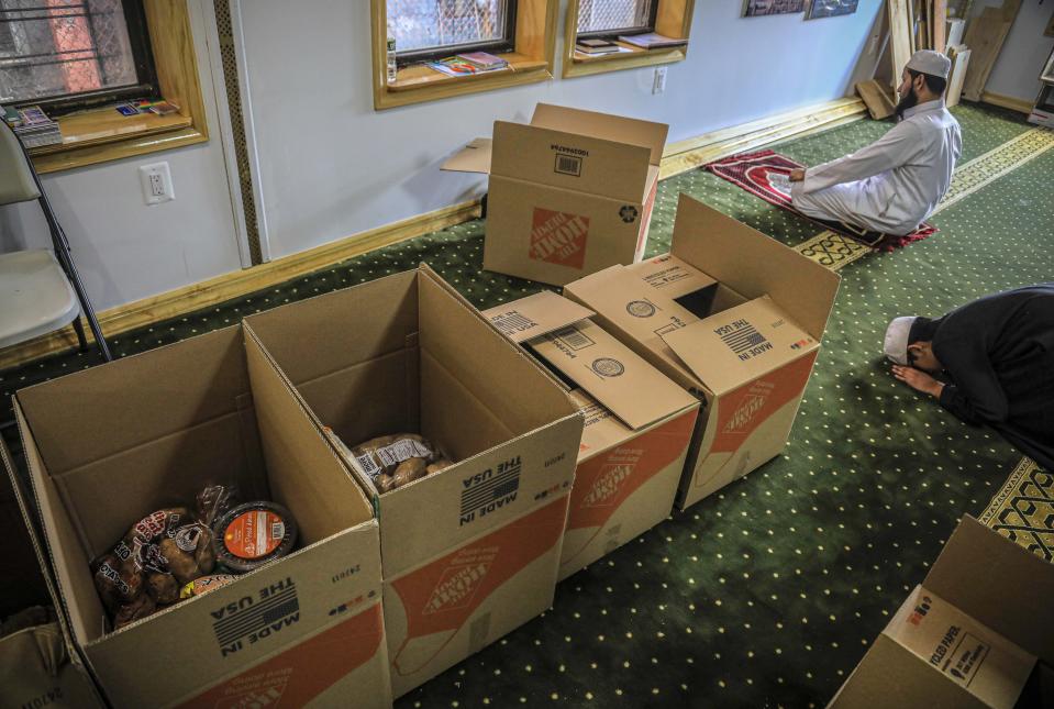 In this Wednesday, April 22, 2020, photo, Imam Mufti Mohammed Ismail, leader of An-Noor Cultural Center and masjid that serves a mostly Bangladeshi Muslim community in the Elmhurst neighborhood in the Queens borough of New York, and his son Hassan, 13, right, pray near boxes of food supplies being prepared for distribution to those impacted by COVID-19 restrictions. Ismaill says this gives the center the opportunity to fulfill one of Ramadan's tenets — to serve those less fortunate, regardless of religion. (AP Photo/Bebeto Matthews)