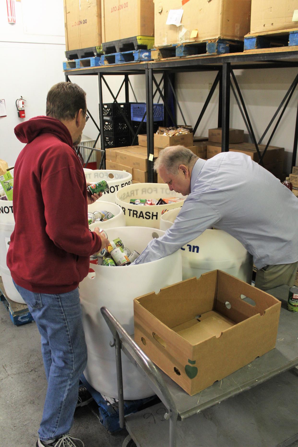 Great Falls Food Bank Executive Director Shaun Tatarka (right) sifts through food donations with warehouse employee Kris Harding