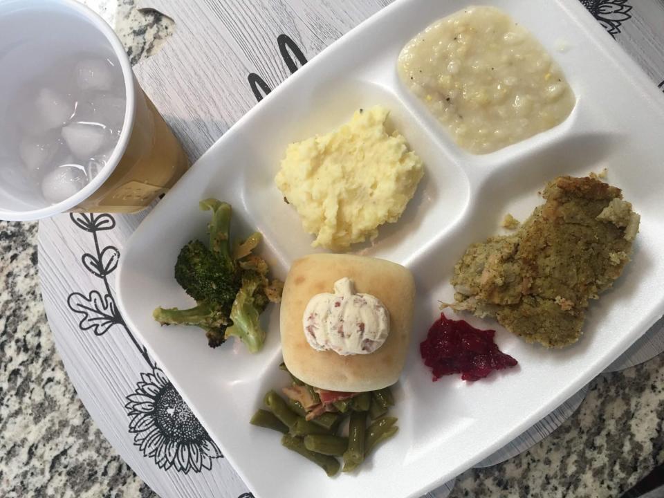 a plate of thanksgiving foods, including a dinner roll with a pumpkin-shaped pat of compound butter