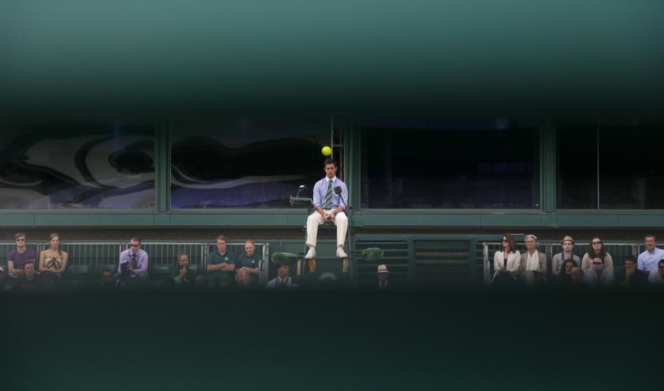 FILE - An umpire watches the ball as a match unfolds on Court 18, as seen through wooden slats, at the All England Lawn Tennis Championships in Wimbledon, London, Wednesday, June 26, 2013. (AP Photo/Anja Niedringhaus, File)