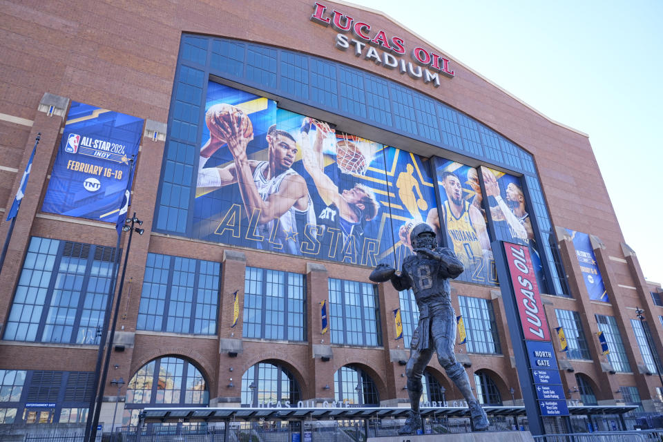 A statue of Indianapolis Colts quarterback Peyton Manning stand in front of signage promoting the NBA All-Star basketball game on the window on Lucas Oil Stadium in Indianapolis, Wednesday, Feb. 14, 2024. The NBA All-Star game in Sunday. (AP Photo/Michael Conroy)