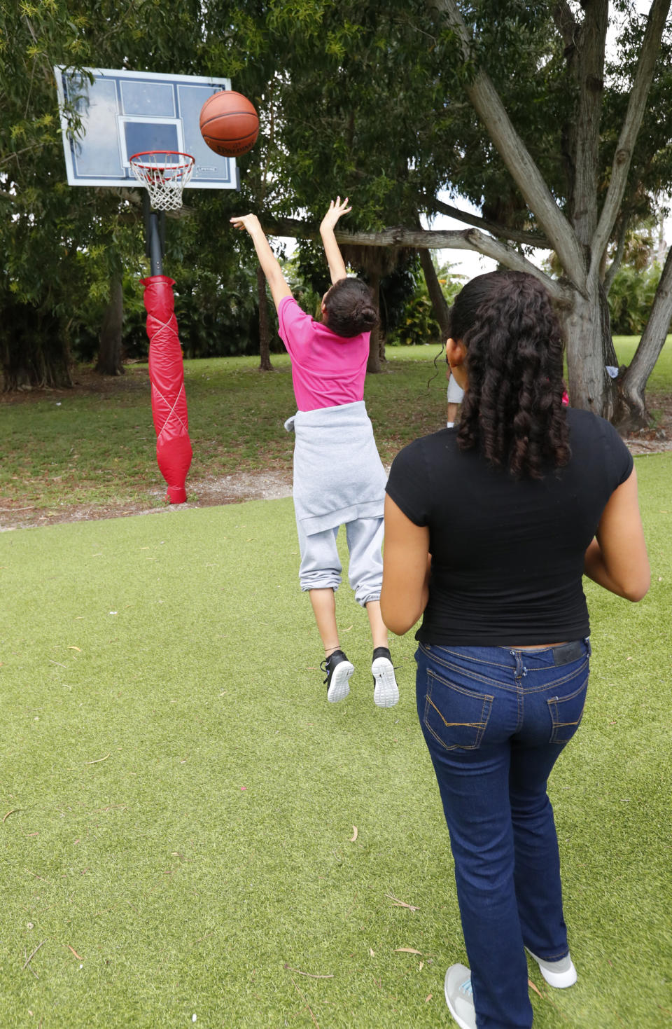 In this Tuesday, Sept. 24, 2019, photo, girls take a shot at basketball while exercising at a shelter for migrant teenage girls, in Lake Worth, Fla. (AP Photo/Wilfredo Lee)