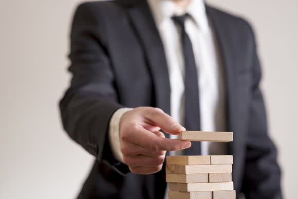 A man in a business suit stacking wooden blocks