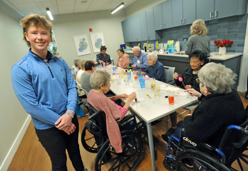 Max Bohane, 15, of Hingham, left, joins residents at The Cordwainer memory care center in Norwell for an Easter egg activity. Max started a pen pal project between the residents and Plymouth River School fifth grade students in Hingham.
