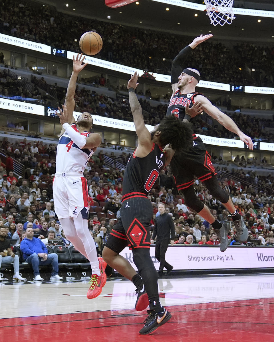 Washington Wizards' Jared Butler (4) shoots over Chicago Bulls' Coby White (0) as Alex Caruso comes over for a block during the first half of an NBA basketball game Monday, March 25, 2024, in Chicago. (AP Photo/Charles Rex Arbogast)