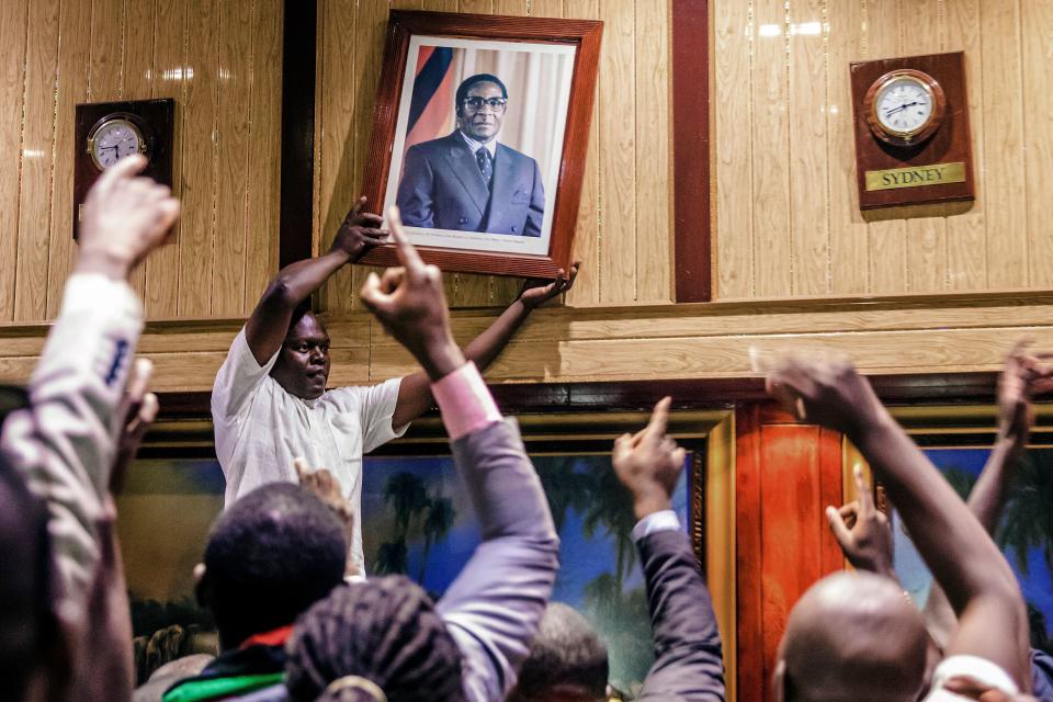 People remove&nbsp;Mugabe's&nbsp;portrait&nbsp;from the wall at the International Conference center.