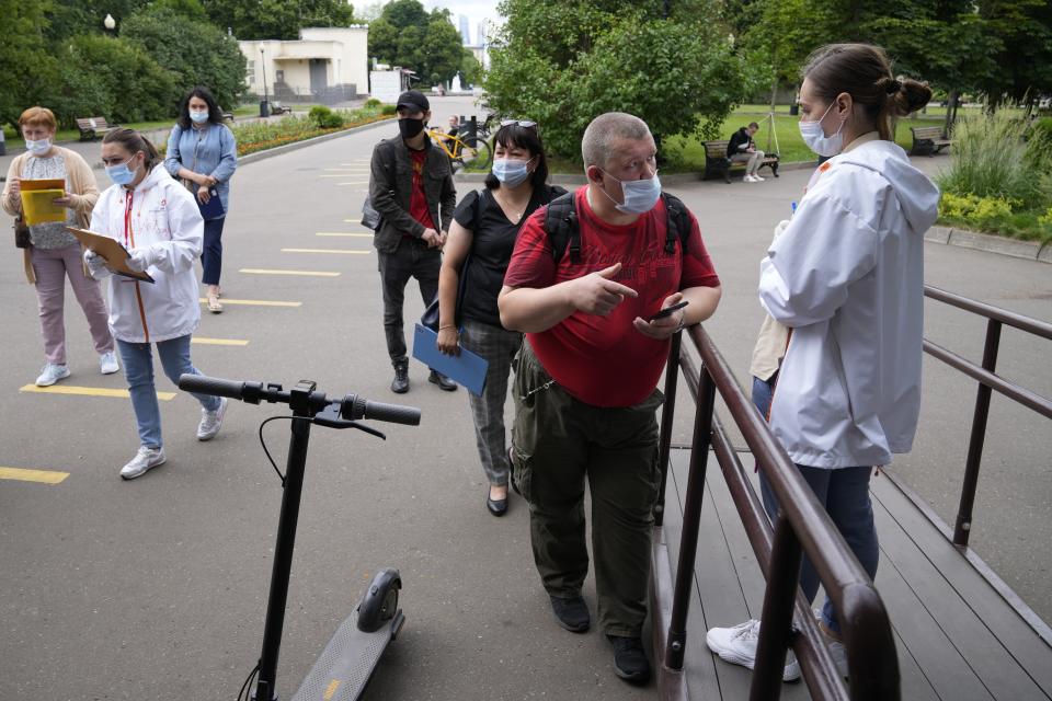 A group of people some of them wearing face masks to protect against coronavirus stand in line to get a coronavirus vaccine at a vaccination point in Gorky Park in Moscow, Russia, Wednesday, June 30, 2021. Russia was among the first in the world to announce and deploy a coronavirus vaccine last year, but so far only about 23 million, just over 15% of the population have received at least one vaccine shot. Hampered by widespread vaccine hesitancy and limited production capacity, Russia's vaccination rates have picked up in recent weeks, after authorities in many regions made shots mandatory for employees in certain sectors. (AP Photo/Alexander Zemlianichenko)