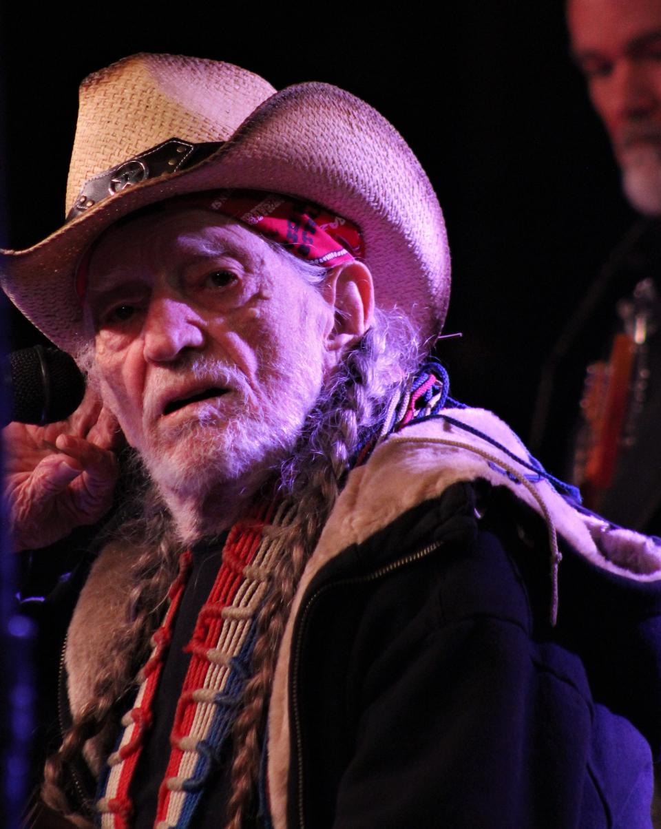 Willie Nelson cups his ear to encourage fans to sing with him during his performance Saturday night at the Outlaws & Legends Music Festival. Willie, almost 90 and with breathing issues, performed seated and spoke-sang many of his songs. His fans didn't mind at all.