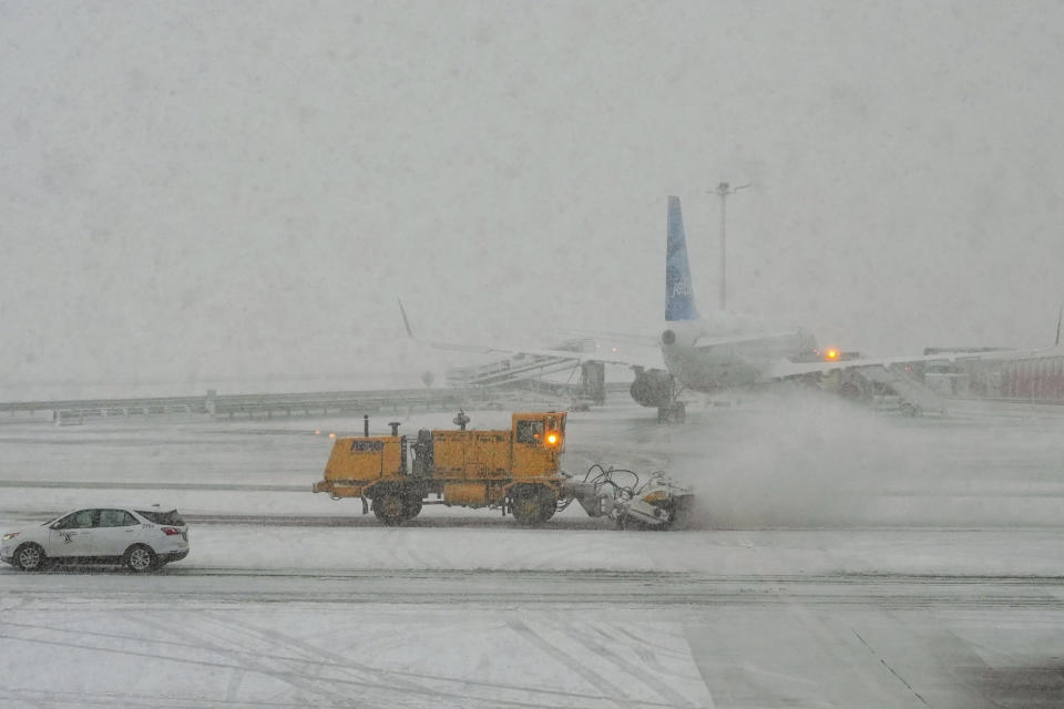 Workers clear the runway as snow falls at John F. Kennedy International Airport, Tuesday, Feb. 13, 2024, in New York. (AP Photo/Frank Franklin II)