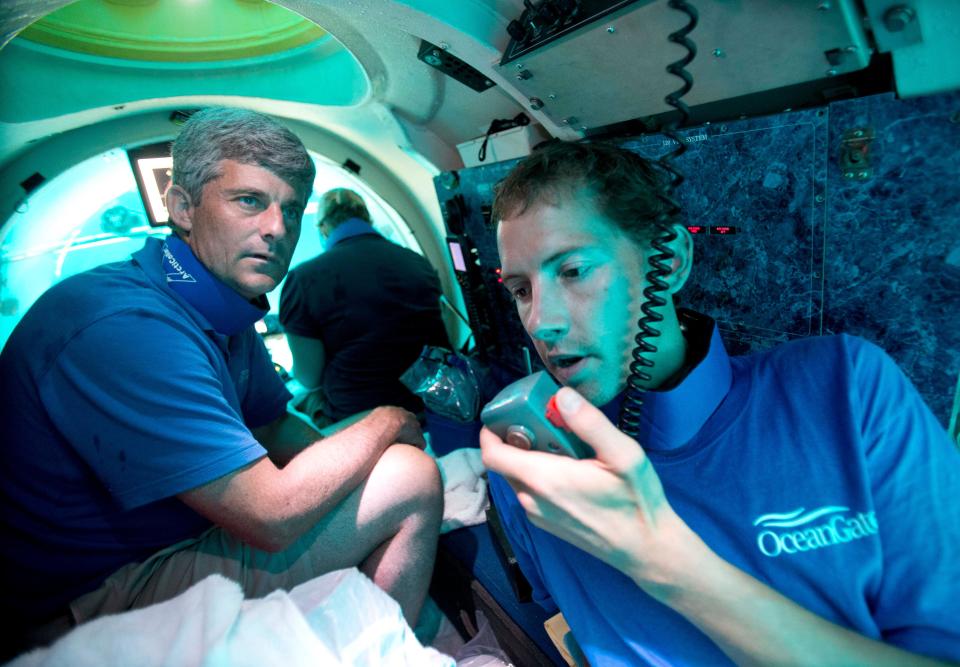 In this Friday, June 28, 2013 photo, submersible pilot Randy Holt, right, communicates with the support boat as he and Stockton Rush, left, CEO and Co-Founder of OceanGate Inc., dive in the company's submersible, 