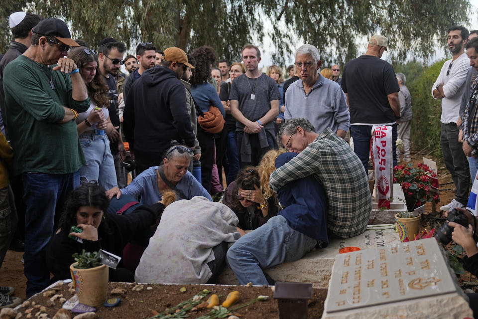 Friends that attended the funeral of 26-year-old Alon Shamriz mourn over the grave of a victim of the Oct. 7th attack buried in the same cemetery in Kibbutz Shefayim, Israel, Sunday Dec. 17, 2023. Shamriz was one of three hostages mistakenly shot to death by Israeli troops Friday in a neighborhood of Gaza City.(AP Photo/Ohad Zwigenberg)