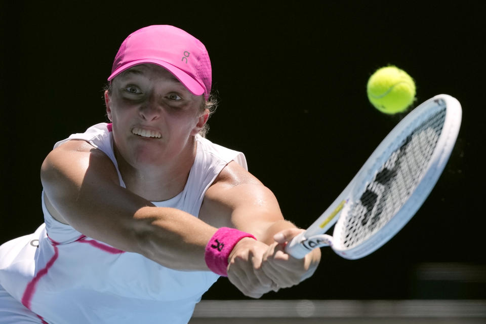 Iga Swiatek of Poland plays a backhand return to Sofia Kenin of the U.S. during their first round match at the Australian Open tennis championships at Melbourne Park, Melbourne, Australia, Tuesday, Jan. 16, 2024. (AP Photo/Andy Wong)