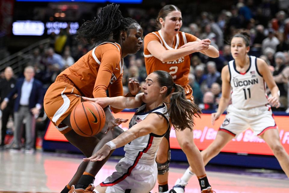 UConn's Nika Muhl, center, passes while under pressure from Texas' Amina Muhammad during their November 2022 game in Storrs, Conn. The teams will play again this December in Austin.