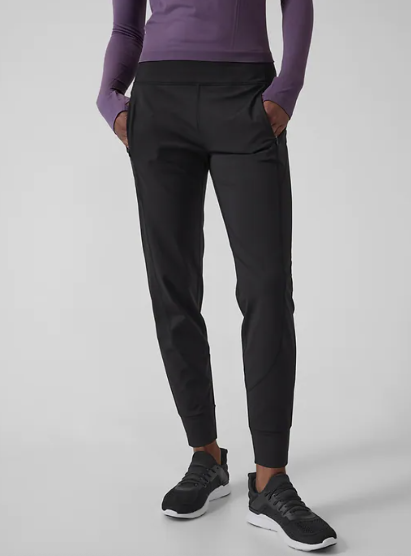 woman wearing purple shirt, black running shoes, and black pants Rainier Jogger (Photo via Athleta)