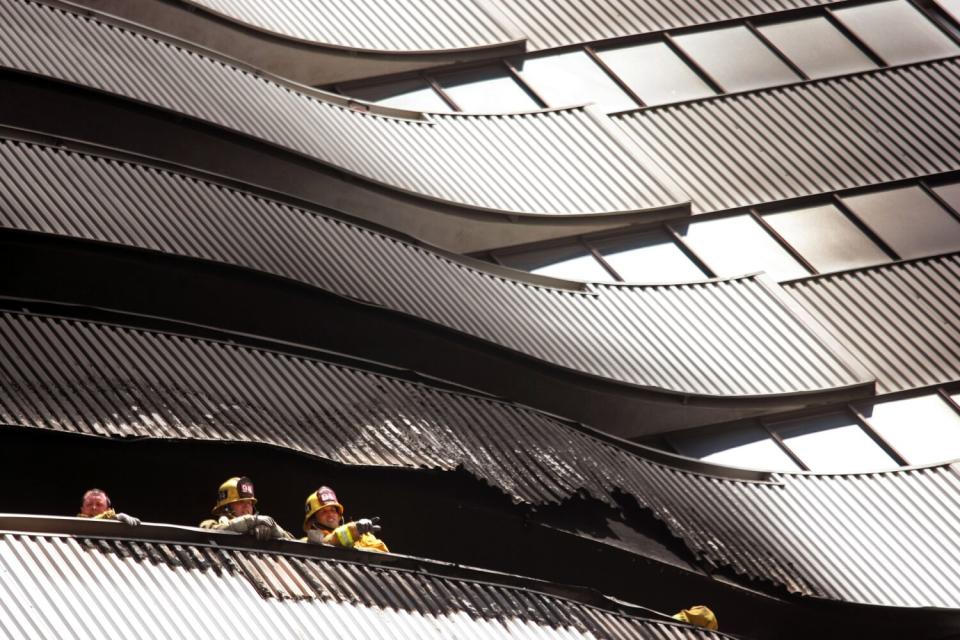 The heads and shoulders of firefighters can be seen behind a railing.