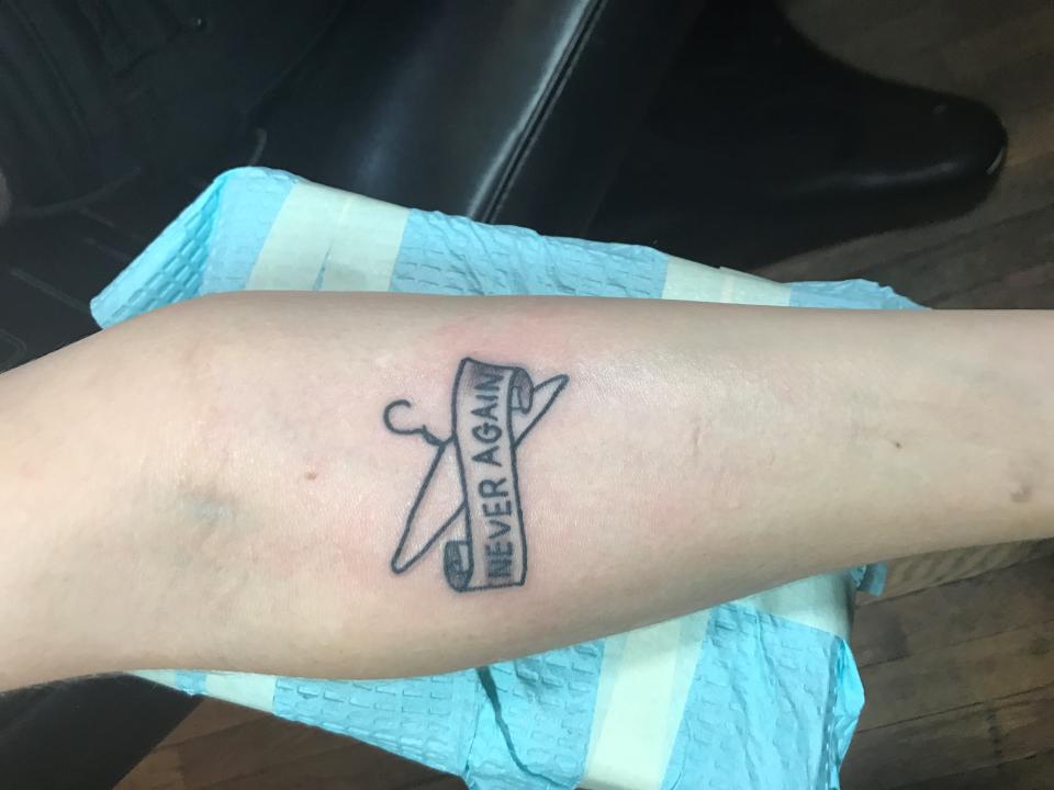 A tattoo of a coat hanger with the words "Never Again" adorns Colleen Krajewski's right forearm.