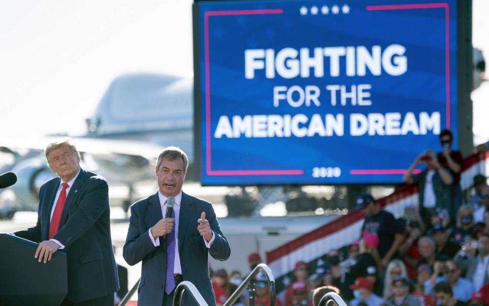 Donald Trump listens as Nigel Farage speaks during a Make America Great Again rally - BRENDAN SMIALOWSKI/AFP via Getty Images