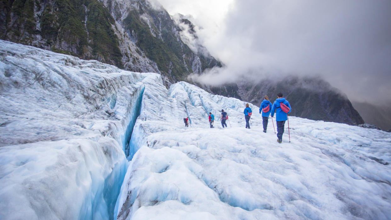  A group crosses a glacier while roped together. 