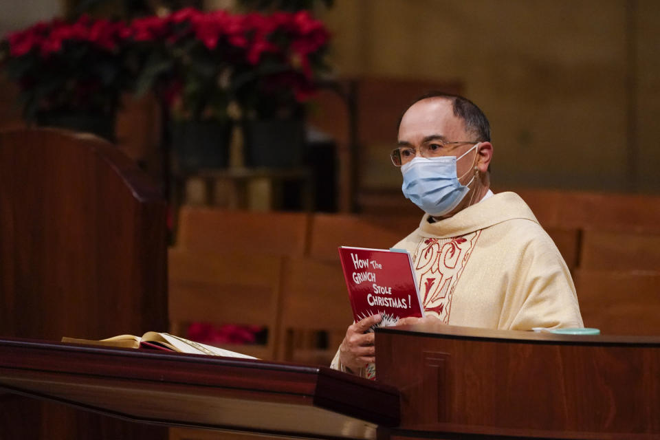 Father David Gallardo holds up a copy of Dr. Seuss' "How the Grinch Stole Christmas" and likens the Grinch to COVID-10 during a Christmas Eve Mass at Cathedral of Our Lady of the Angels Thursday, Dec 24, 2020, in Los Angeles. California became the first state to record 2 million confirmed coronavirus cases, reaching the milestone on Christmas Eve as nearly the entire state was under a strict stay-at-home order and hospitals were flooded with the largest crush of cases since the pandemic began. (AP Photo/Ashley Landis)