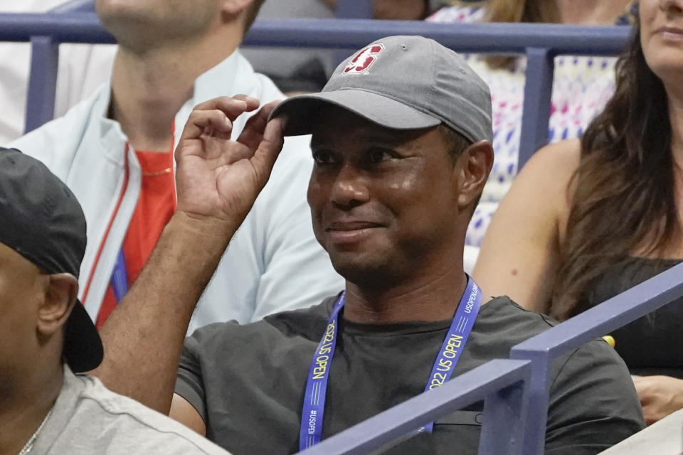 FILE - Tiger Woods tips his hat to the crowd during a match between Serena Williams and Anett Kontaveit, of Estonia, in the second round of the U.S. Open tennis championships, Wednesday, Aug. 31, 2022, in New York. Woods has won the Player Impact Program on the PGA Tour despite playing only three times. He is likely to play three unofficial events in December.(AP Photo/John Minchillo, File)