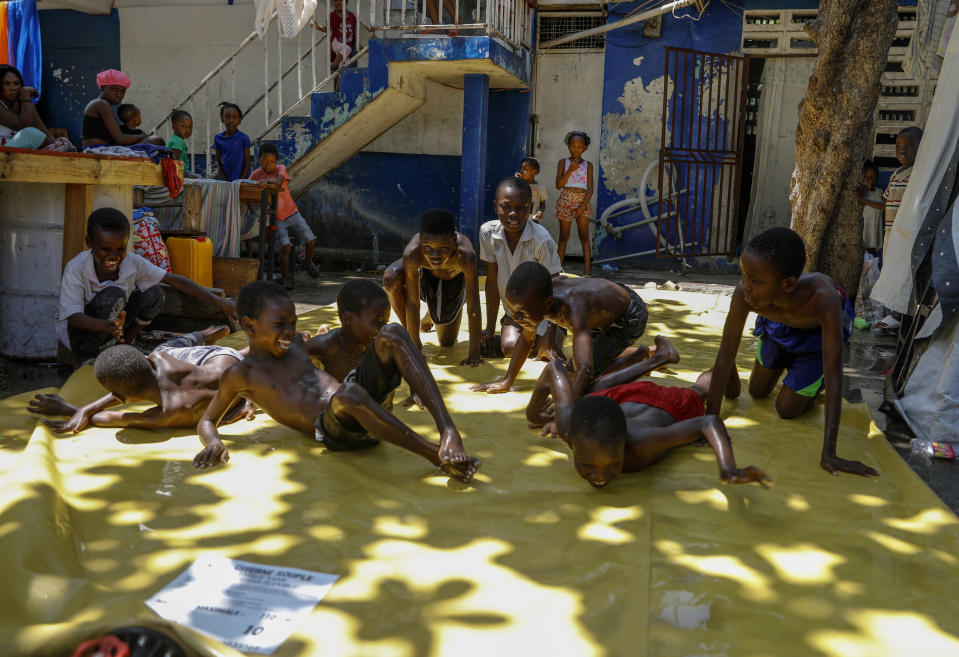 Children play on a slip-and-slide at a shelter for families displaced by gang violence, in Port-au-Prince, Haiti, Friday, March 22, 2024. (AP Photo/Odelyn Joseph)