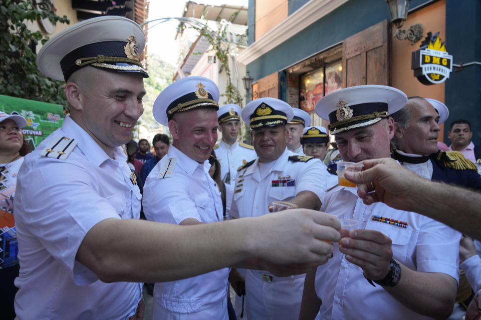 Miembros de tripulación rusos brindan con una bebida tradicional venezolana en una visita de bienvenida con autoridades en La Guaira, Venezuela, después de que la fragata Almirante Gorshkov y el buque petrolero Akademik Pashin de la Armada rusa atracaran en puerto, el martes 2 de julio de 2024. (AP Foto/Ariana Cubillos)