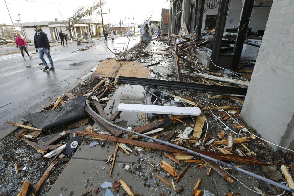 People pass by businesses destroyed by storms Tuesday, March 3, 2020, in Nashville, Tenn. Tornadoes ripped across Tennessee early Tuesday, shredding buildings and killing multiple people. (AP Photo/Mark Humphrey)