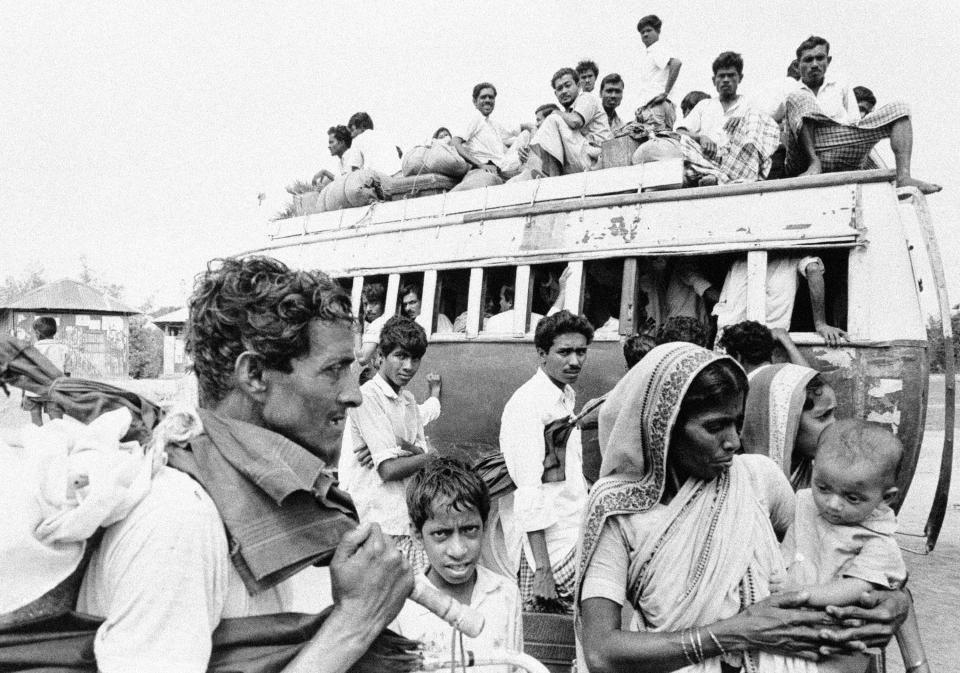 FILE - In this April 11, 1971, file photo, a bus fully laden with Bengali refugees prepares to leave as more of them wait for transport in a suburb of Dacca. Bangladesh is celebrating 50 years of independence this year. (AP Photo/Michel Laurent, File)